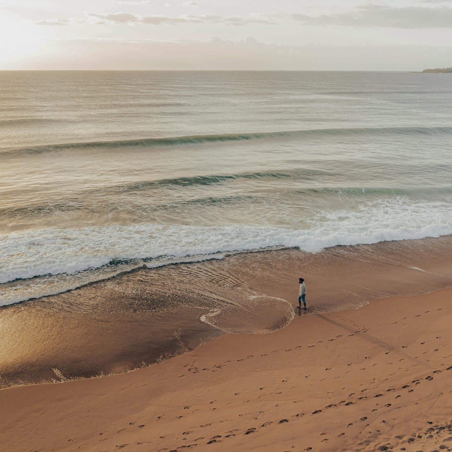 Figure walking along a Port Stephens beach at low tide